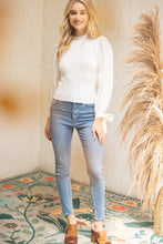 Load image into Gallery viewer, Woman wearing a white blouse and blue jeans standing in a room with decorative elements.
