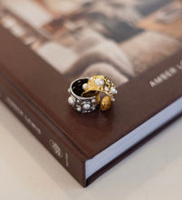 Load image into Gallery viewer, Gold and silver ring with pearls on a book
