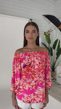 Load and play video in Gallery viewer, Julian Chang's Andrea Top Island Print: a vibrant island print top with a pink and orange color palette and bell sleeves, perfect for adding a playful touch to your outfit.
